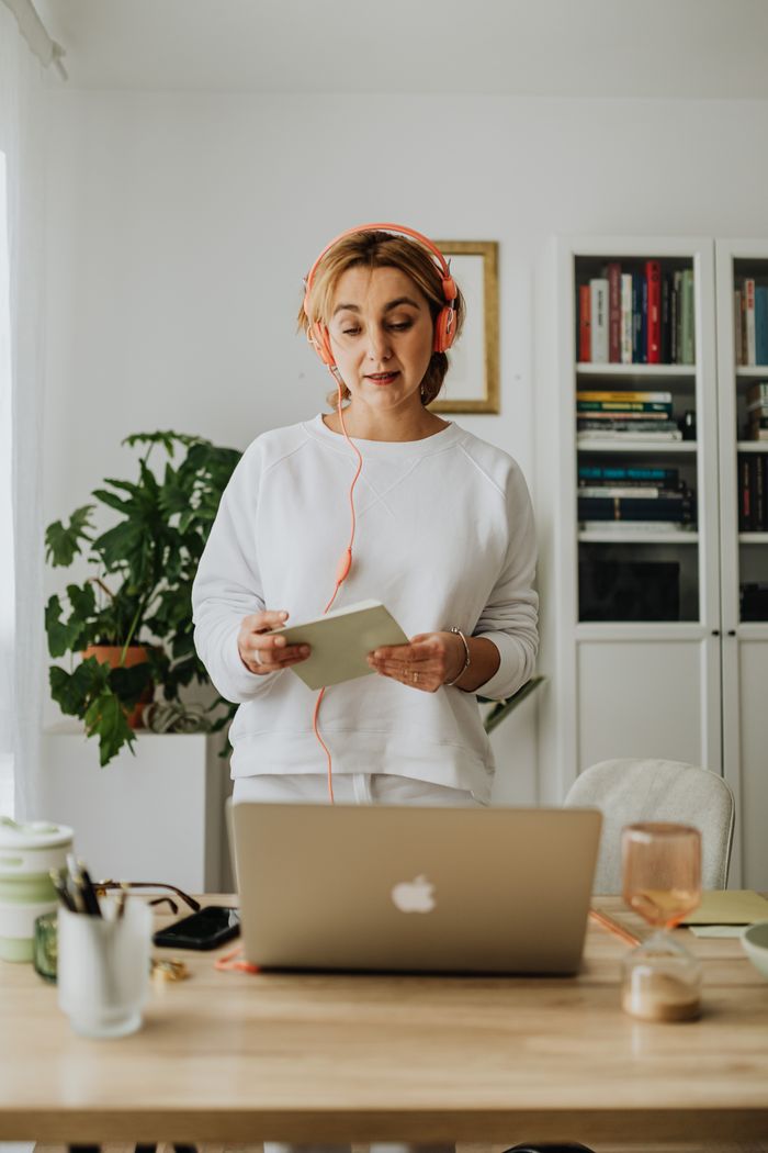 Une femme portant un casque anime un webinaire en ligne depuis son bureau à domicile.